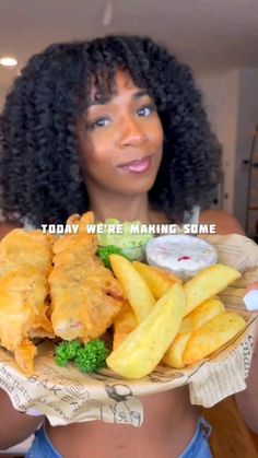 a woman holding a plate with fish and fries on it that says today we're making some