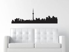 a white couch sitting in front of a wall with a black city skyline on it