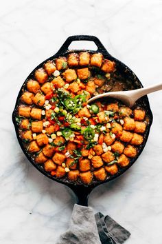 a skillet filled with tater tots on top of a white countertop