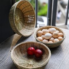 three baskets filled with eggs sitting on top of a wooden table