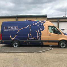 a blue and gold van parked in front of a building with a horse painted on it's side