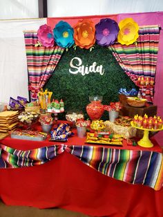 there is a table with food on it and flowers around the table that says suda