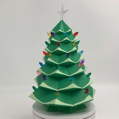 an origami christmas tree with lights on it's base and a star hanging from the top