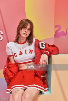 a woman sitting on a bench wearing a red skirt and white shirt with the word'cat