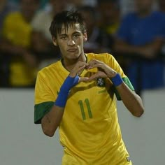 a soccer player is making a heart sign with his hands while the crowd looks on