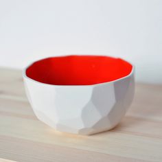 a white and red bowl sitting on top of a wooden table