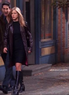 the young couple are walking down the street together, one is wearing black boots and the other has a brown coat