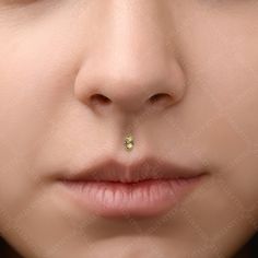 a woman's nose with a tiny yellow jewel in the middle of her nose