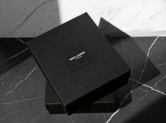 two black boxes sitting next to each other on top of a marble countertop,