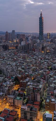 an aerial view of a city with tall buildings in the foreground and skyscrapers lit up at night