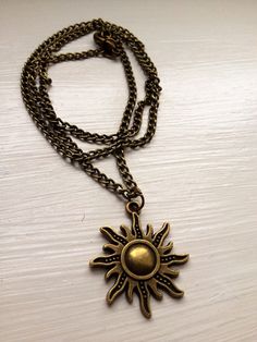 a gold necklace with a sun charm hanging from it