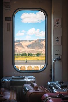 two suitcases sitting next to each other in front of an open window on a train