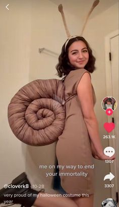 a woman in a brown dress holding a large round object on her back and smiling at the camera