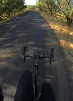 a person riding a bike down a road with trees on both sides and grass to the side