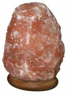 a large pink rock sitting on top of a wooden stand in front of a white background