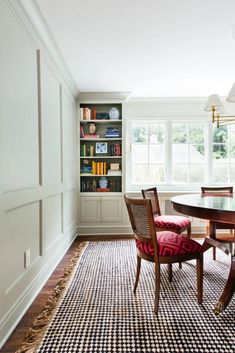 a dinning room table with chairs and bookshelves in the back ground area