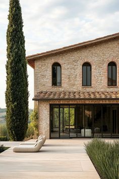 an outdoor patio with chaise lounges in front of a stone and brick house