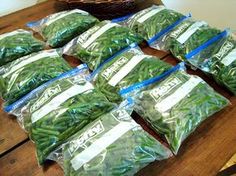 several bags of green beans sitting on top of a wooden table