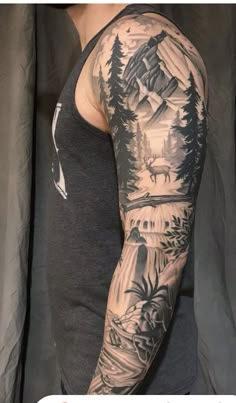 a man's arm with trees and mountains tattooed on the back of his arm