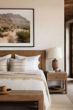 a bed with white sheets and pillows in a bedroom next to a painting on the wall