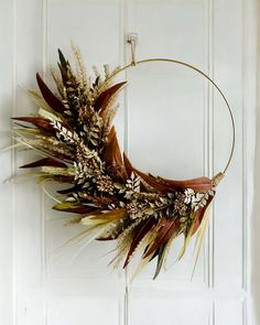 a wreath with dried flowers and leaves hanging on a door