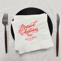 a napkin with the words married christmas on it next to a fork and knife sitting on a black plate