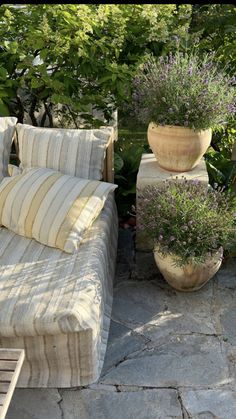 a couch sitting on top of a stone floor next to potted plants and flowers