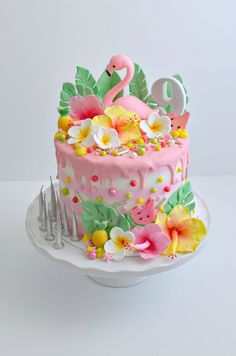 a flamingo themed birthday cake with pink frosting and flowers on a white plate