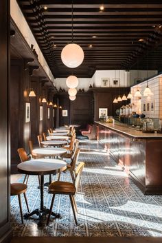 a restaurant with tables and chairs lined up against the wall, along with lights hanging from the ceiling