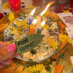 a person holding a piece of paper in front of a cake with candles