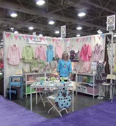 a woman standing in front of a booth with clothing on display