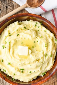 a wooden bowl filled with mashed potatoes and butter