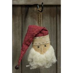 an old fashioned christmas ornament hanging on a wooden door with a red and white santa hat