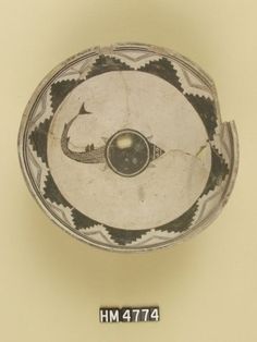 an old black and white bowl with a fish on it's side is shown