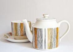 a white tea pot and saucer sitting next to each other on top of a plate