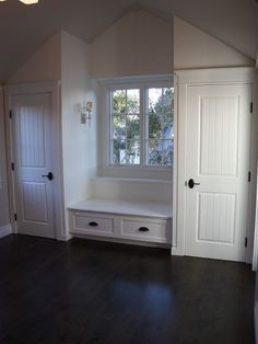 an empty room with two white doors and a bench in the middle of the room