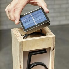 a person holding a solar panel on top of a wooden box