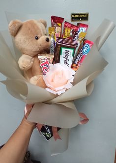 a teddy bear sitting on top of a bouquet of chocolates and candy bar wrappers