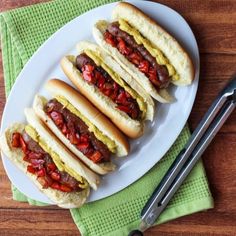 three hot dogs on buns with ketchup and relish sitting on a plate