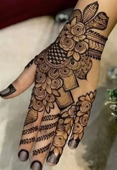 a henna tattoo on the palm of someone's hand with flowers and leaves