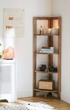 a wooden shelf with books and candles on it next to a white cabinet in a room