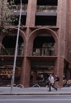 two people walking down the street in front of a building