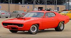 an orange muscle car parked in front of a building