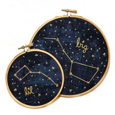 two embroidered hoops with zodiac signs on them, one in gold and the other in blue