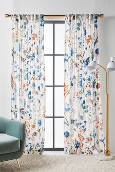 a living room with floral curtains and a blue chair