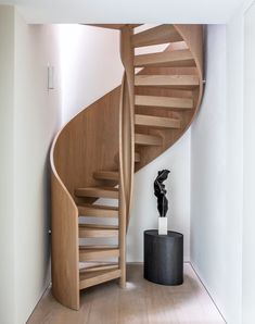 a wooden spiral staircase next to a black vase