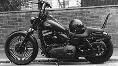 a black and white photo of a motorcycle parked in front of a brick wall with a helmet on it