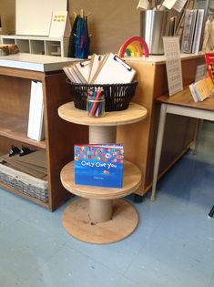 three tiered shelf with books and other items on it in a library or craft room