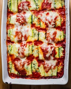 a casserole dish with zucchini, cheese and sauce in it on a wooden table