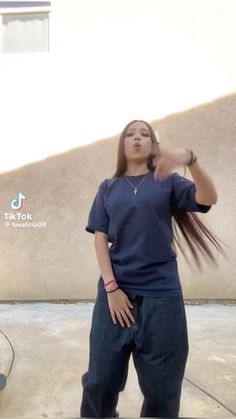 a woman standing in front of a building with her hair blowing back and looking up